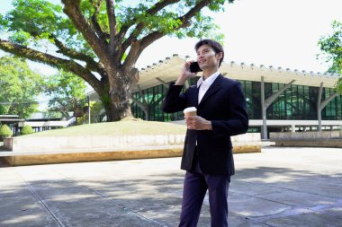 Genç iş adamı kahve molasında dışarıdaki ofis binasından arıyor. Sokaklarda yürüyen bir iş adamı...