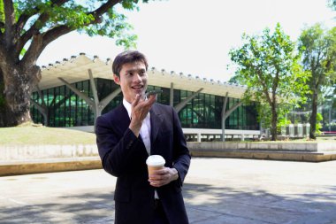 Genç iş adamı kahve molasında dışarıdaki ofis binasından arıyor. Sokaklarda yürüyen bir iş adamı...