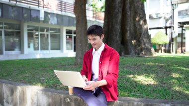 Erkek girişimci açık havada melez olarak oturuyor. Mutlu iş adamı girişimci ofis dışında dizüstü bilgisayar kullanarak başka tarafa bakıyor. Boşluğu kopyala..