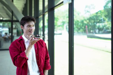 Genç bir adam sesli komut kullanıyor ya da akıllı telefonuyla yapay zeka asistanı ile iletişim kuruyor..