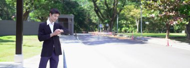 Siyah takım elbiseli bir işadamı kahve fincanı tutuyor, saatine bakıyor ve taksi bekliyor..