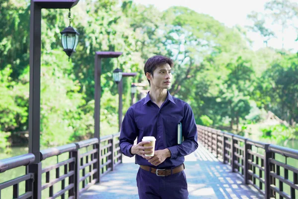 Elinde kahve fincanı olan bir adam ya da bahçede duran yeşil doğa arka planında duran tek kullanımlık kahve ve kitap. Mutlu insanları boş vakitlerinde kabul et ve kahve iç...