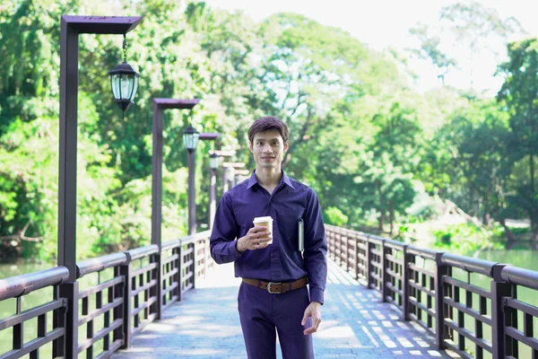 Elinde kahve fincanı olan bir adam ya da bahçede duran yeşil doğa arka planında duran tek kullanımlık kahve ve kitap. Mutlu insanları boş vakitlerinde kabul et ve kahve iç...