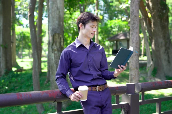 Elinde kahve fincanı olan bir adam ya da bahçede duran yeşil doğa arka planında duran tek kullanımlık kahve ve kitap. Mutlu insanları boş vakitlerinde kabul et ve kahve iç...