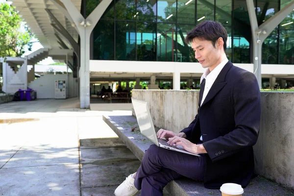 Girişimci açık havada melez bir şekilde çalışıyor. Mutlu iş adamı girişimci ofis dışında dizüstü bilgisayar kullanarak başka tarafa bakıyor. Boşluğu kopyala..