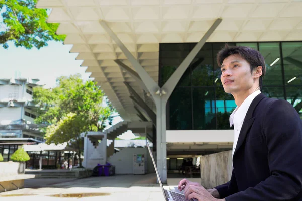 Girişimci açık havada melez bir şekilde çalışıyor. Mutlu iş adamı girişimci ofis dışında dizüstü bilgisayar kullanarak başka tarafa bakıyor. Boşluğu kopyala..
