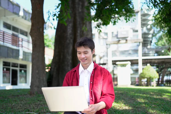 Erkek girişimci açık havada melez olarak oturuyor. Mutlu iş adamı girişimci ofis dışında dizüstü bilgisayar kullanarak başka tarafa bakıyor. Boşluğu kopyala..