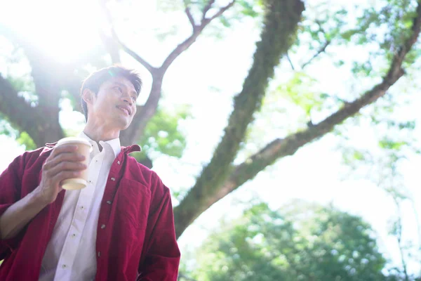 Şehir merkezindeki caddede dikilen genç adam kahve içiyor. Dışarıdaki kasaba yaşam tarzları..