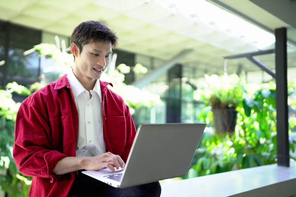 Erkek girişimci açık havada melez olarak oturuyor. Mutlu iş adamı girişimci ofis dışında dizüstü bilgisayar kullanarak başka tarafa bakıyor. Boşluğu kopyala..