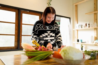 Woman in the kitchen preparing homemade food, female hands working with fresh vegetables.