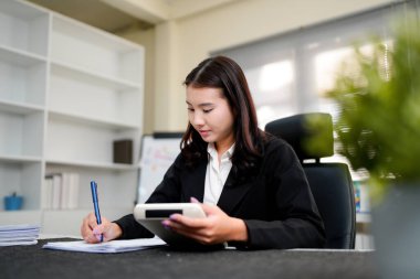 Finans belgesi ve mali muhasebe kavramının rakamlarını hesaplamak için hesap makinesi kullanan bir iş kadını.