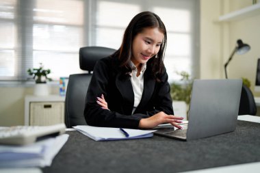 Bir iş kadını dizüstü bilgisayar klavyesine yazarken, elinin yansıması olan bir dijital tablet de çevrimiçi çalışmayı ve uzaktan istihdamı temsil eden bir ofis masasının üzerinde bulunuyor...