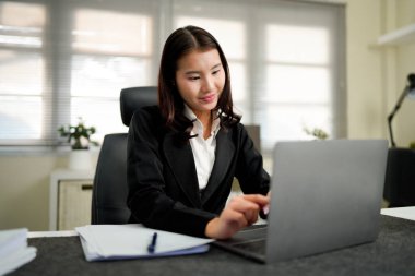 Ofiste çalışan dizüstü bilgisayarı ve evrakları olan bir iş kadını..