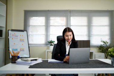 Ofiste çalışan dizüstü bilgisayarı ve evrakları olan bir iş kadını..