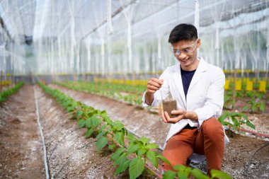 Araştırmacı tarımsal uygulamaları geliştirmek ve sürdürülebilir tarımı desteklemek amacıyla bir bitki yetiştirme alanında toprak analizi yürütüyor..