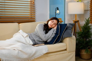 Evdeki kanepede kitap okurken uyuyan güzel bir genç kadın..