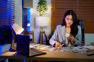 Kadın mimar malzemeleri seçiyor. Örnekleri bitirerek karşılaştırıyor. Kadın iç mimari, kumaş spektrumlu yenileme malzemeleri seçiyor..