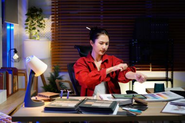 Kadın iç mimar gece geç saatlere kadar loş ışıklı stüdyosunda çalışıyor..