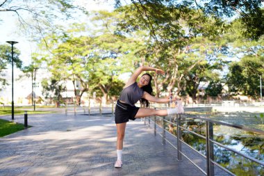 Spor eğitimi için ısınırken esneme hareketleri yapan mutlu bayan sporcu..