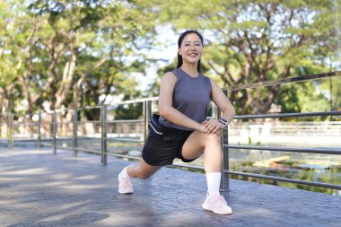 Spor eğitimi için ısınırken esneme hareketleri yapan mutlu bayan sporcu..