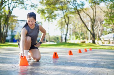 Bayan sporcu parkta bir külahla antrenmana hazırlanıyor..
