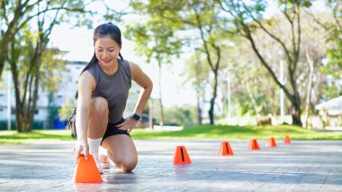 Bayan sporcu parkta bir külahla antrenmana hazırlanıyor..
