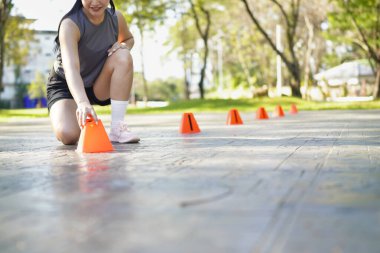 Bayan sporcu parkta bir külahla antrenmana hazırlanıyor..