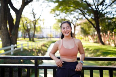 Atletik kız başını çevirir ve kameraya samimi bir şekilde gülümser, pozitiflik ve mutluluk saçar..