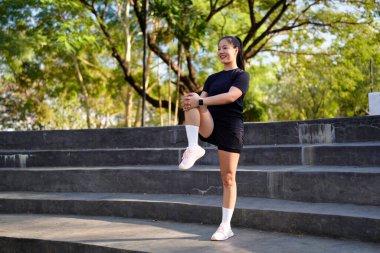 Spor eğitimi için ısınırken esneme hareketleri yapan mutlu bayan sporcu..