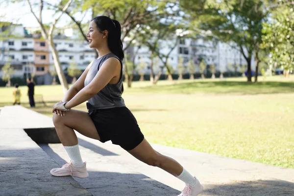 Spor eğitimi için ısınırken esneme hareketleri yapan mutlu bayan sporcu..