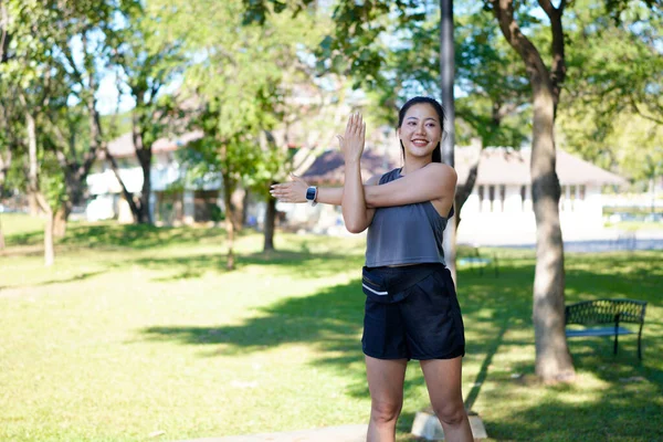 Spor eğitimi için ısınırken esneme hareketleri yapan mutlu bayan sporcu..