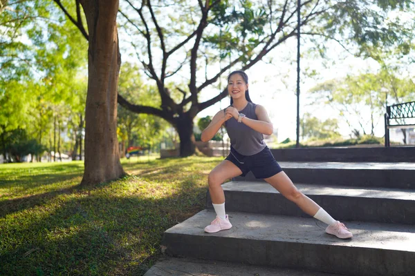 Spor eğitimi için ısınırken esneme hareketleri yapan mutlu bayan sporcu..