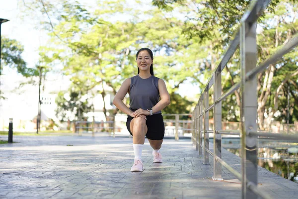 Spor eğitimi için ısınırken esneme hareketleri yapan mutlu bayan sporcu..