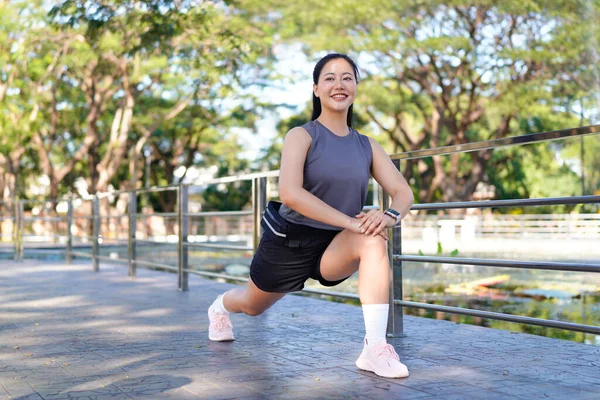 Spor eğitimi için ısınırken esneme hareketleri yapan mutlu bayan sporcu..