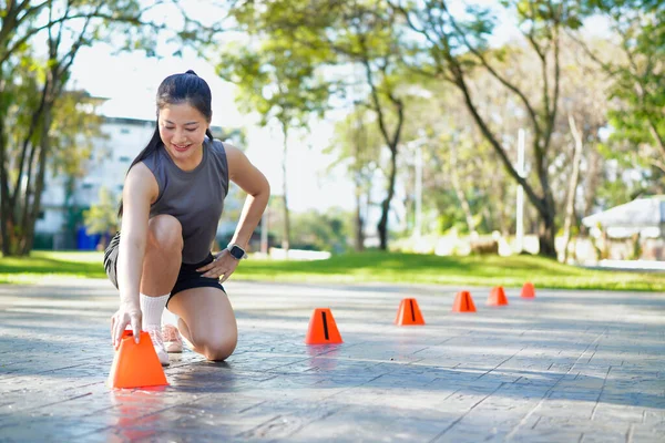 Bayan sporcu parkta bir külahla antrenmana hazırlanıyor..