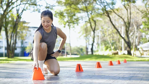 Bayan sporcu parkta bir külahla antrenmana hazırlanıyor..