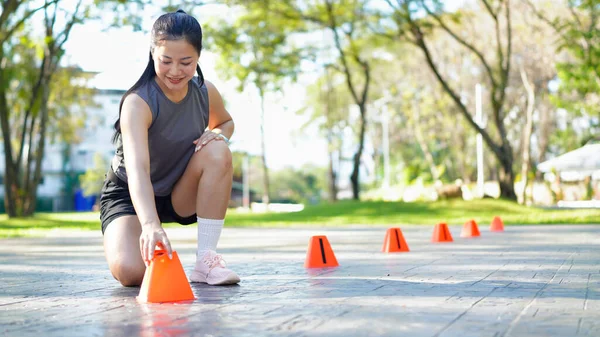 Bayan sporcu parkta bir külahla antrenmana hazırlanıyor..