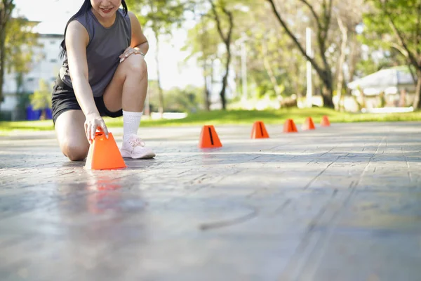 Bayan sporcu parkta bir külahla antrenmana hazırlanıyor..