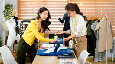 Yeni moda koleksiyonunda birlikte çalışan iki kadın giysi tasarımcısının fotoğrafı..