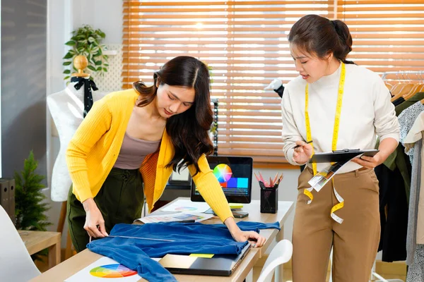 Yeni moda koleksiyonunda birlikte çalışan iki kadın giysi tasarımcısının fotoğrafı..