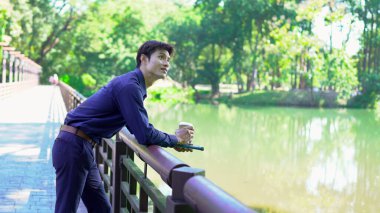 Elinde kahve fincanı olan bir adam ya da bahçede duran yeşil doğa arka planında duran tek kullanımlık kahve ve kitap. Mutlu insanları boş vakitlerinde kabul et ve kahve iç...