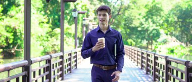 Elinde kahve fincanı olan bir adam ya da bahçede duran yeşil doğa arka planında duran tek kullanımlık kahve ve kitap. Mutlu insanları boş vakitlerinde kabul et ve kahve iç...