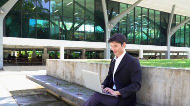 Girişimci açık havada melez bir şekilde çalışıyor. Mutlu iş adamı girişimci ofis dışında dizüstü bilgisayar kullanarak başka tarafa bakıyor. Boşluğu kopyala..