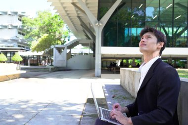 Girişimci açık havada melez bir şekilde çalışıyor. Mutlu iş adamı girişimci ofis dışında dizüstü bilgisayar kullanarak başka tarafa bakıyor. Boşluğu kopyala..