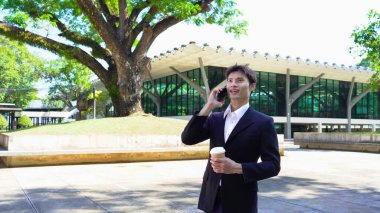 Genç iş adamı kahve molasında dışarıdaki ofis binasından arıyor. Sokaklarda yürüyen bir iş adamı...