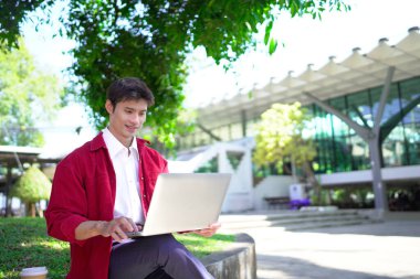Erkek girişimci açık havada melez olarak oturuyor. Mutlu iş adamı girişimci ofis dışında dizüstü bilgisayar kullanarak başka tarafa bakıyor. Boşluğu kopyala..