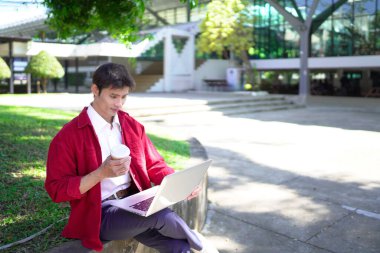Erkek girişimci açık havada melez olarak oturuyor. Mutlu iş adamı girişimci ofis dışında dizüstü bilgisayar kullanarak başka tarafa bakıyor. Boşluğu kopyala..