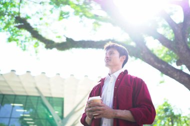 Şehir merkezindeki caddede dikilen genç adam kahve içiyor. Dışarıdaki kasaba yaşam tarzları..