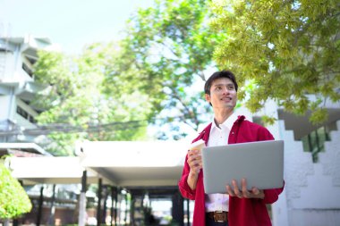 Uzaktan çalışan, kahve içen ve şehir parkında dizüstü bilgisayar kullanan bir adam..