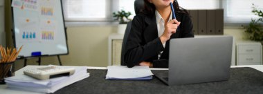 Ofiste çalışan dizüstü bilgisayarı ve evrakları olan bir iş kadını..